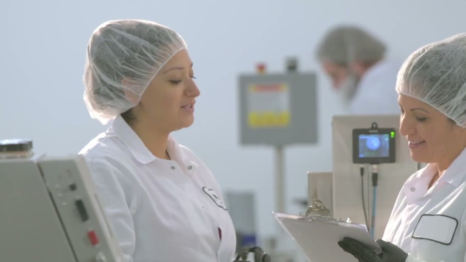 Two technicians in hairnets checking a lot before release