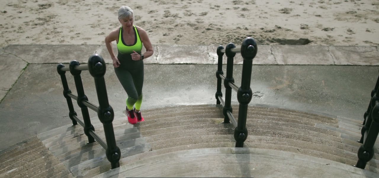 A woman in her sixties running up a flight of outdoor steps without touching the rail