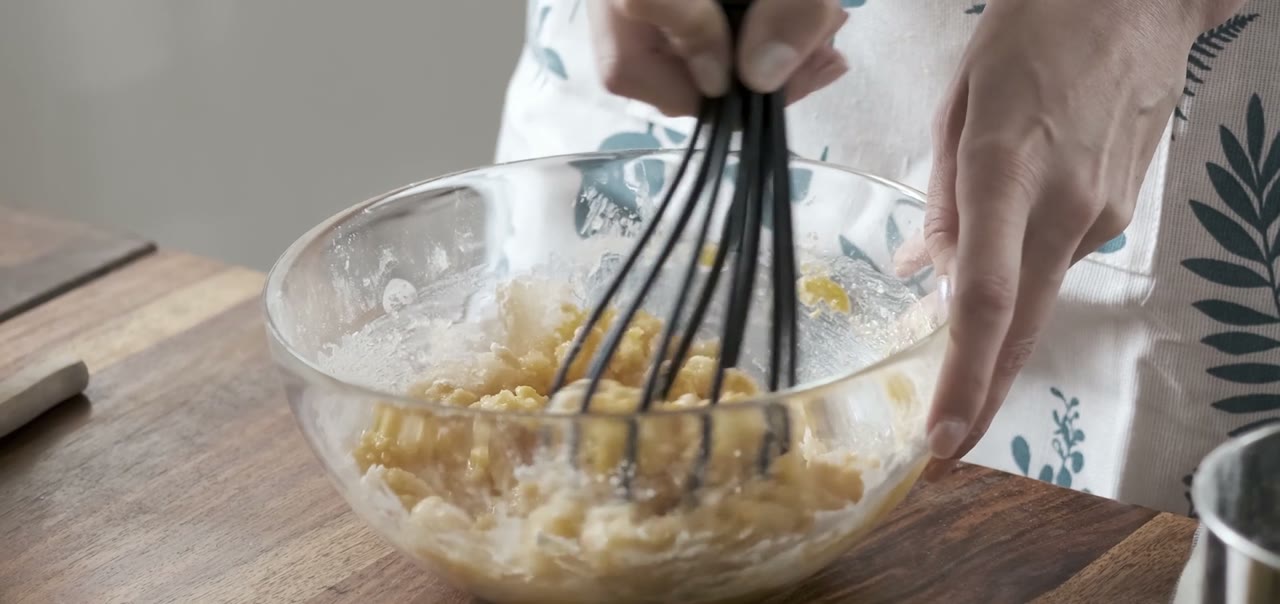 Hands struggling to grip a whisk over a mixing bowl
